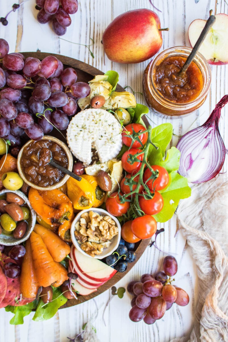 A vegan cheese platter with vegetables, chutney, and cashew cheese