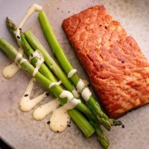 A 3D printed vegan salmon filet on a plate next to some asparagus