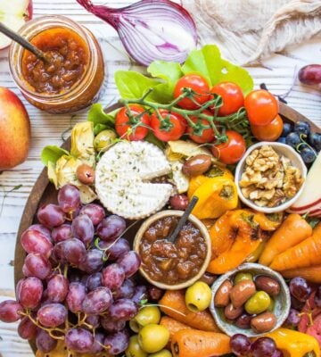 A vegan cheese platter with vegetables, chutney, and cashew cheese