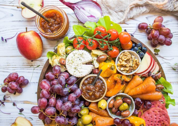 A vegan cheese platter with vegetables, chutney, and cashew cheese