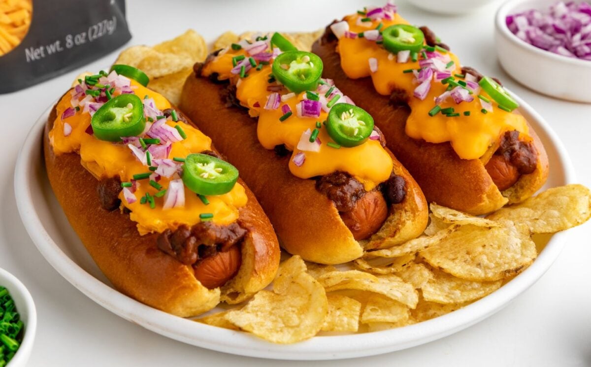 Three vegan chili dogs with melted cheese and chillis on them