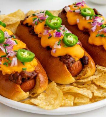 Three vegan chili dogs with melted cheese and chillis on them