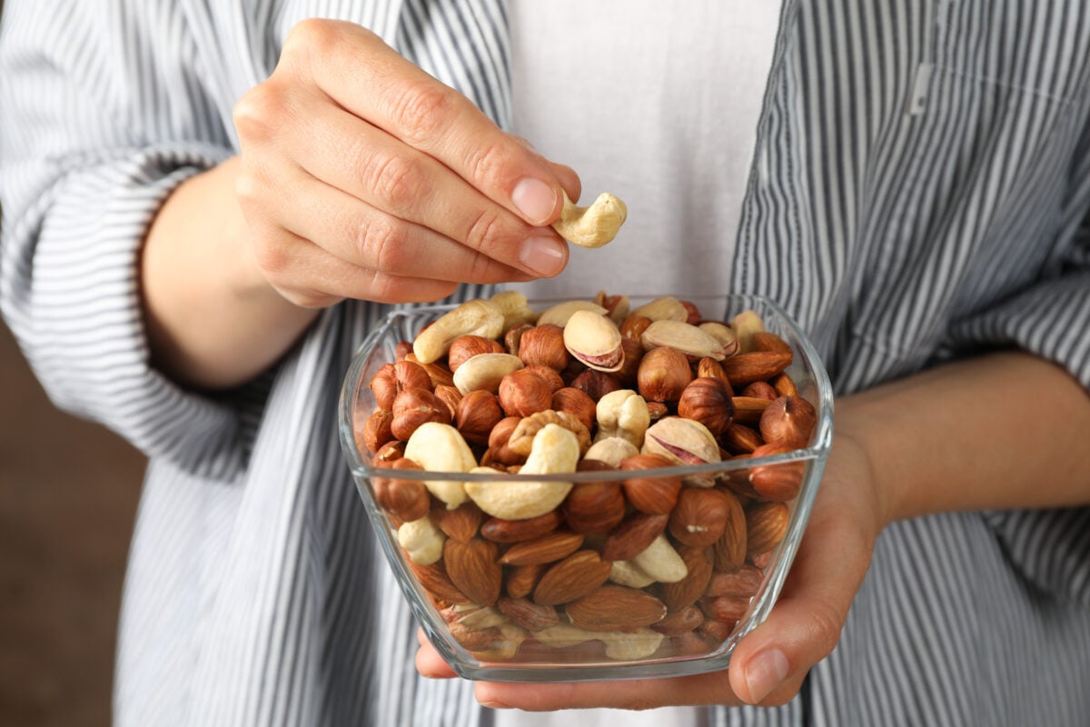 A person eating a bowl of nuts, a food which may lower the risk of Parkinson's