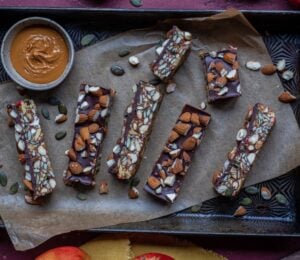 Vegan energy bars on a baking tray next to some apples and nut butter