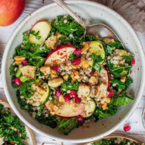 A vegan kale salad with apple, cashew cheese, and pomegranate