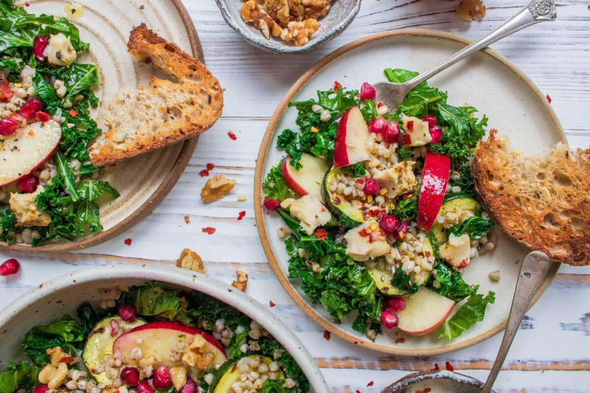 A vegan kale salad with apple, cashew cheese, and pomegranate