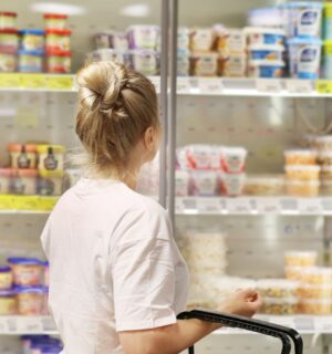 A woman shopping for vegan yogurt at a supermarket