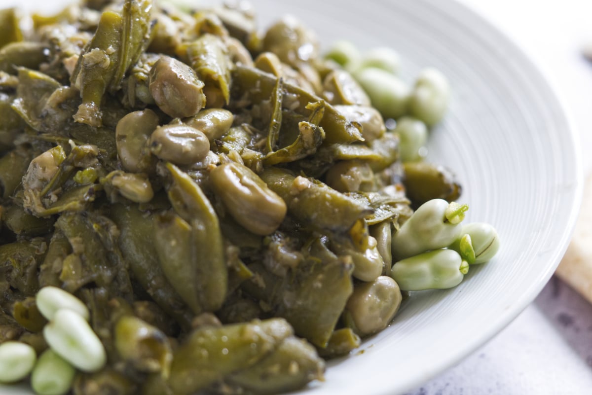 A lebanese vegan dish consisting of garlicky broad beans on a white plate