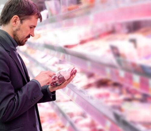 A man picking up a pack of meat in the supermarket in the UK, where meat consumption has fallen significantly