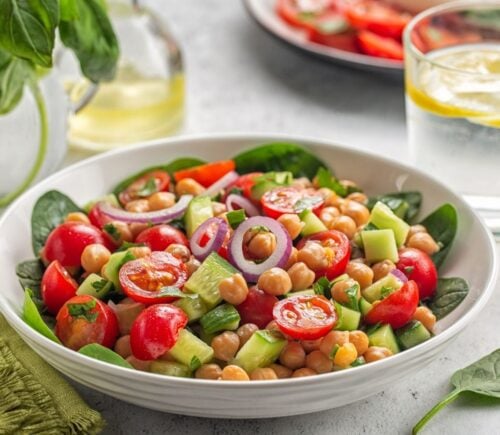 Bowl of healthy plant-based salad with vegan protein chickpeas, tomatoes and onions