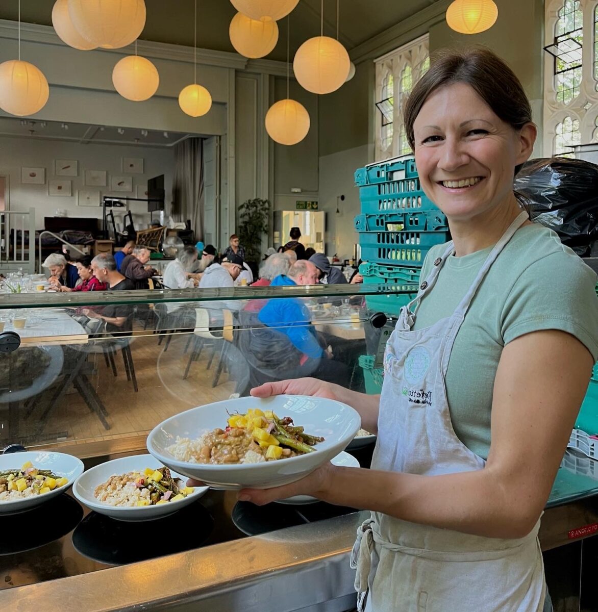 Woman serving food at west London community kitchen Refettorio Felix 