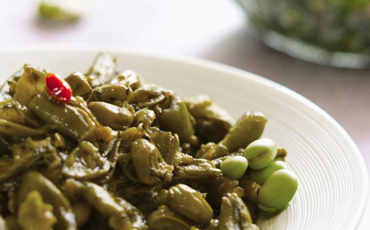 A lebanese vegan dish consisting of garlicky broad beans on a white plate