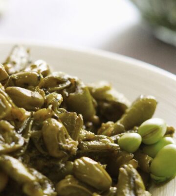 A lebanese vegan dish consisting of garlicky broad beans on a white plate