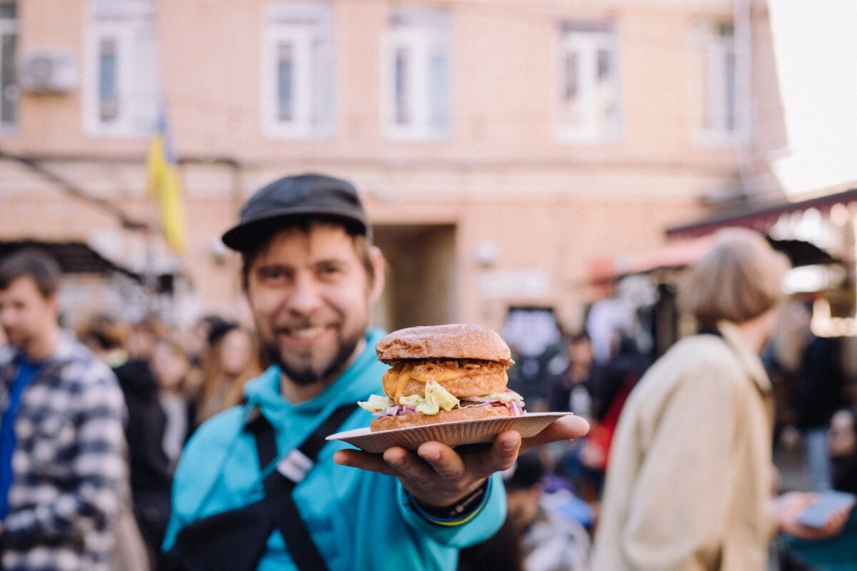 A man in Ukraine holding up a plant-based burger at a vegan festival