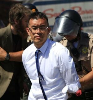 Direct Action Everywhere animal activist Wayne Hsiung being held in handcuffs by police