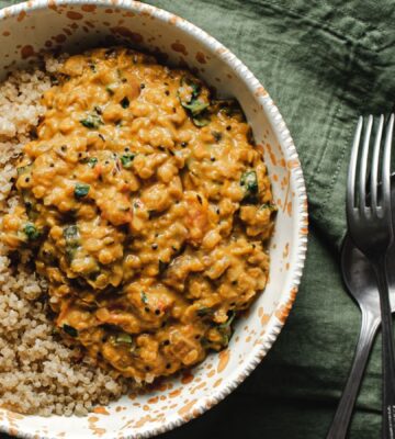 A bowl of butternut squash dahl and grains on a green towel
