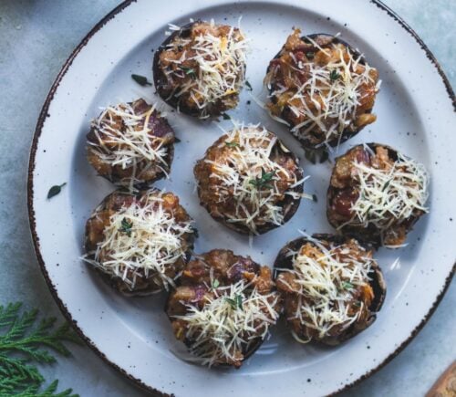 A vegan cheese, bacon, and apple stuffed mushroom being served at a Christmas party