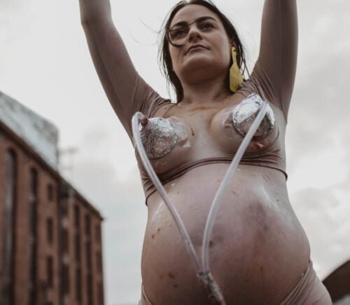A vegan advocate being "milked" outside the Tate Liverpool in an art installation