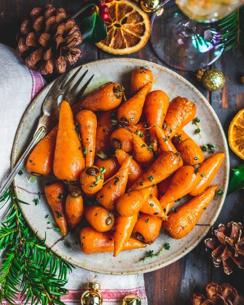 The photo shows a plate of small, maple roasted carrots decorated with garnish.