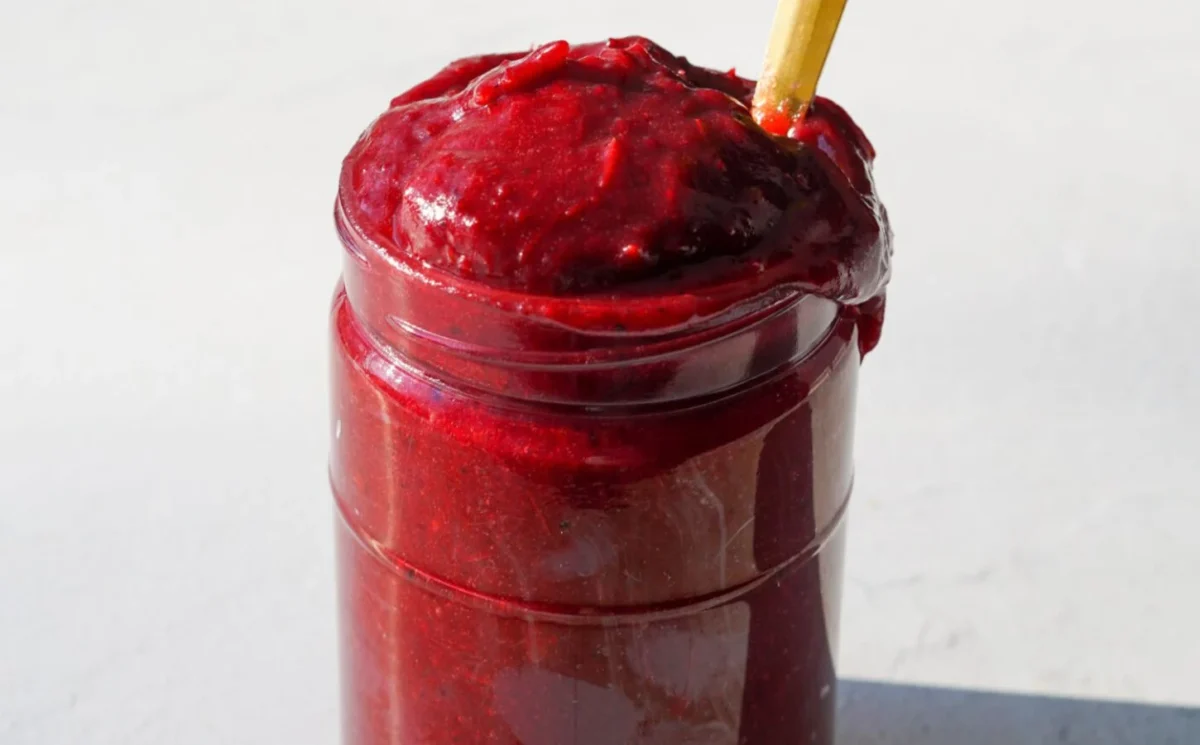 Photo shows a jar overflowing with bright red cranberry butter.