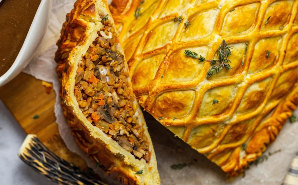 Photo shows a vegan lentil and mushroom wellington cut open to show inside the pastry.