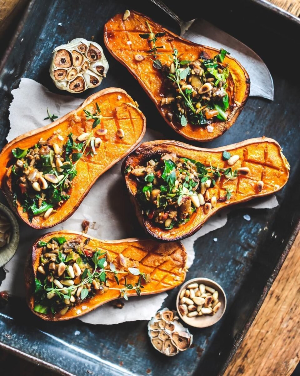 Photo shows a four baked butternut squash halves filled with garlic mushrooms and pine nuts.