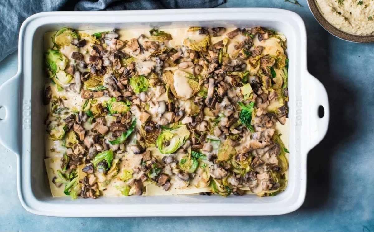 Photo shows a brussel sprout and mushrooms lasagna complete with creamy vegan ricotta sauce.