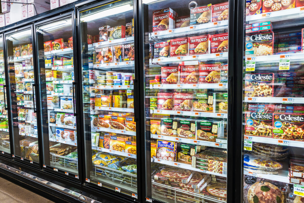 Photo shows refrigerators in a supermarket full of various brightly colored packaged products.