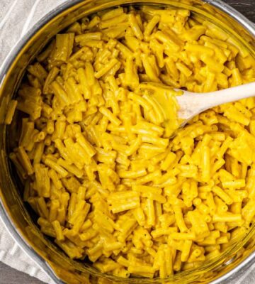 A big pot of vegan mac and cheese with a spoon ready for serving