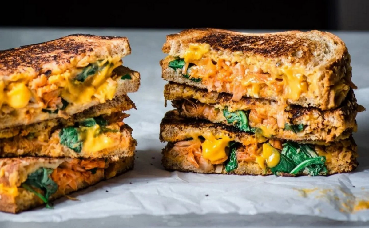 Photo shows a vegan grilled cheese and jackfruit sandwich sliced to show the filling.