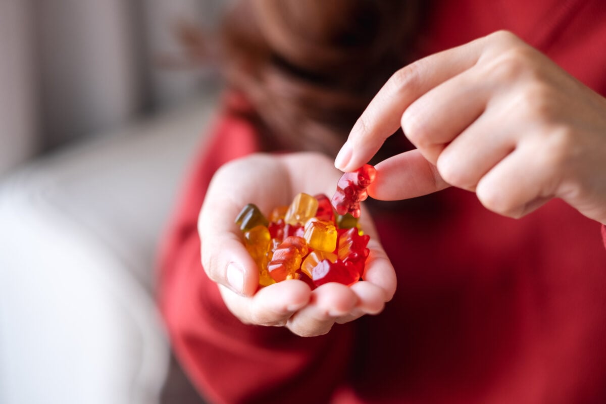 Closeup image shows a woman holding a handful of gummy bears.