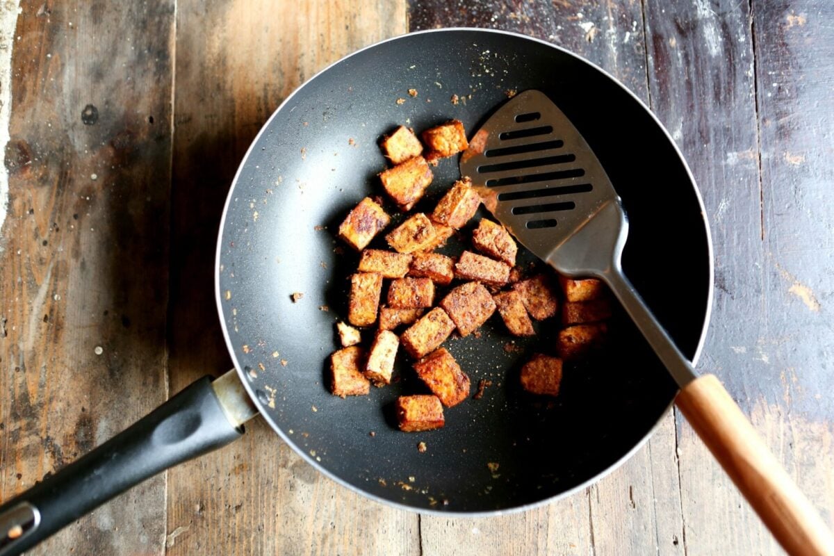 Photo shows a wok full of cubed and seasoned tofu.
