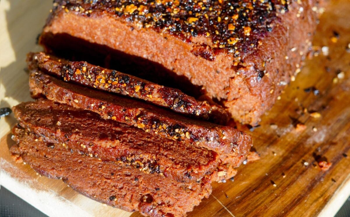 Photo shows a vegan seitan beef-style roast charred and carved on a plate.