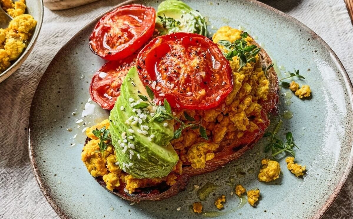 Photo shows a slice of toast topped with a tofu scramble, avocado, and tomatoes.