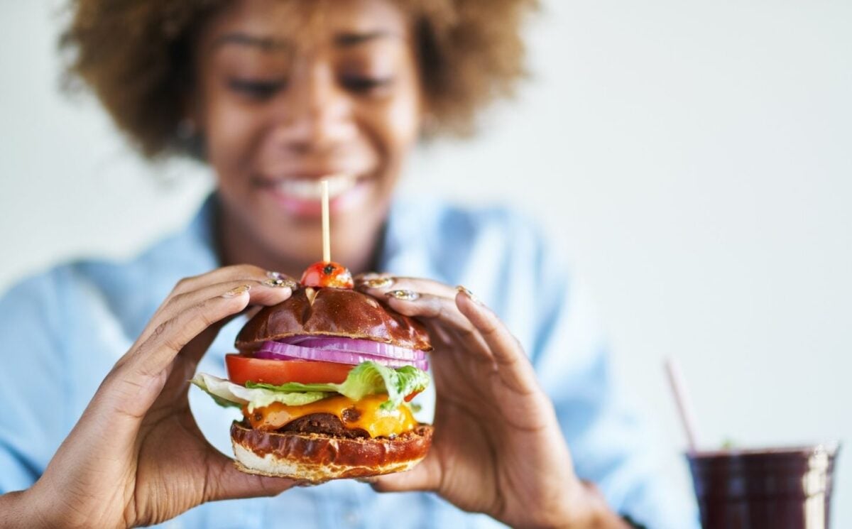 Woman holding a big vegan burger, one of 2.5 million vegans in the UK