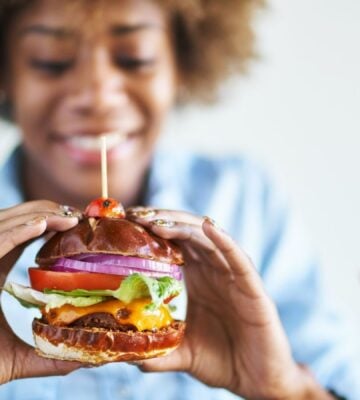 Woman holding a big vegan burger, one of 2.5 million vegans in the UK