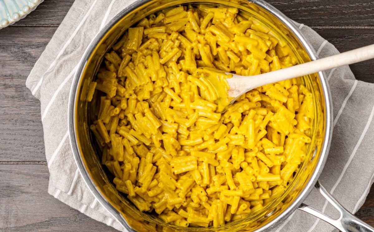 Photo shows a large pan of bright yellow mac and cheese, prepared to a vegan recipe using vegetables and nooch.