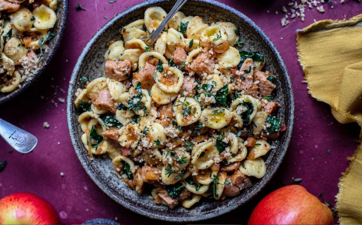 Photo shows a large bowl of sausage and kale pasta prepared using a vegan comfort food recipe.