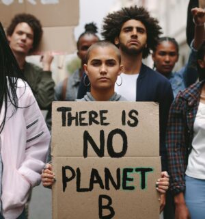 Environmental protestors standing still - one holds a sign reading "There is no planet B"