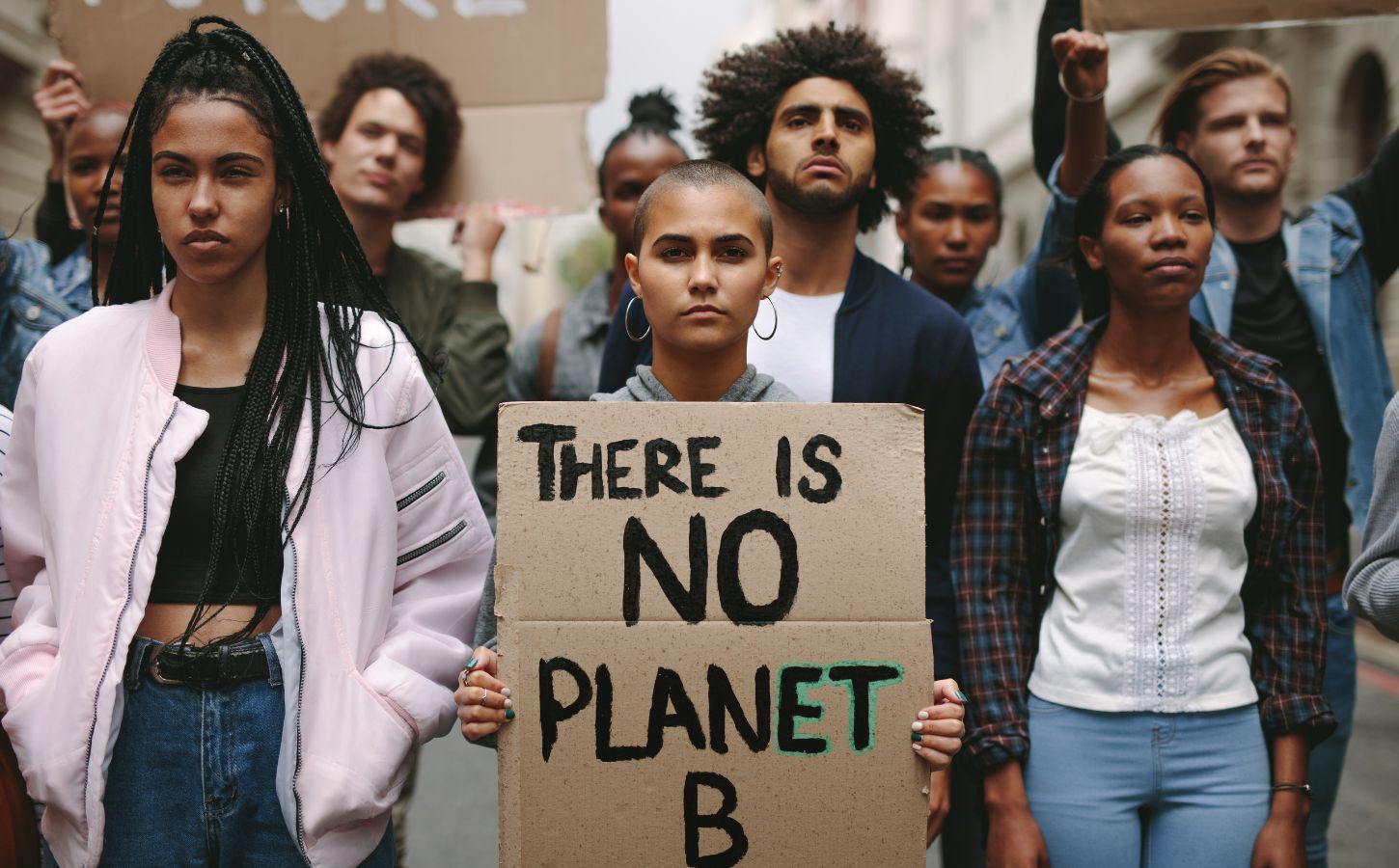 Environmental protestors standing still - one holds a sign reading "There is no planet B"