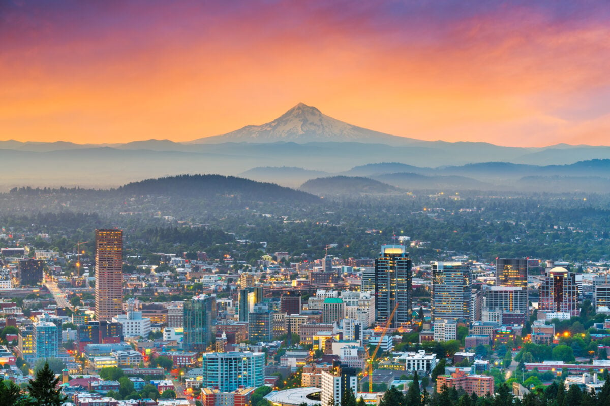 Photo depicts the skyline of downtown Portland, Oregon, with Mt. Hood visible in the background
