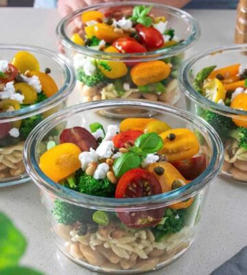 A vegan bean, orzo, pesto salad, all divided into separate containers for meal-prepping