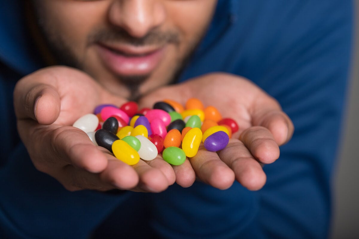 A man holding a pile of jelly beans, which often contain non-vegan ingredient shellac