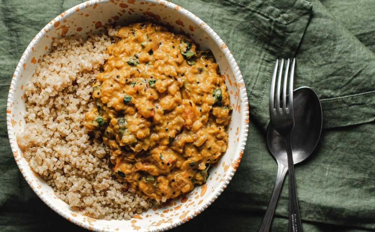 Photo shows a white bowl of butternut squash dhal served with quinoa
