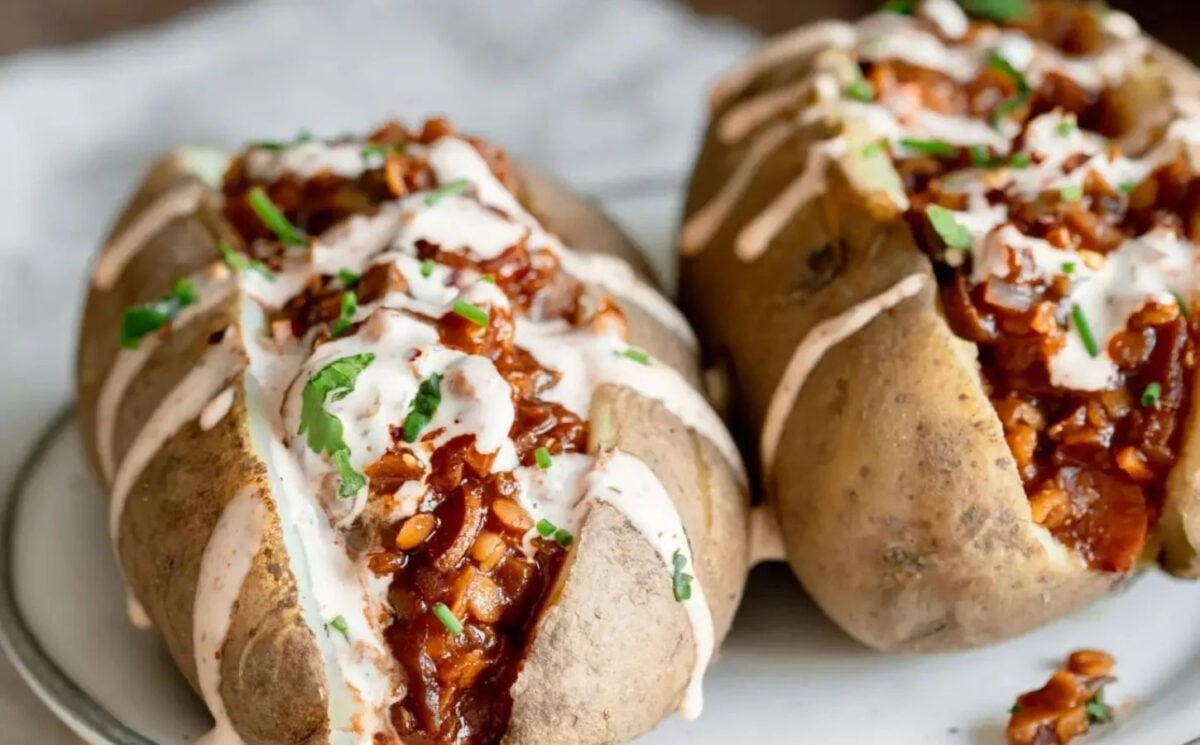 Photo shows two baked potatoes topped with BBQ lentils and a drizzle of sriracha mayo