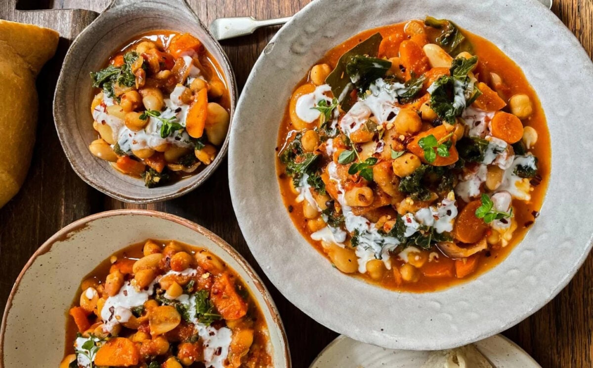 Photo shows three dishes of stew made with beans, kale, and lemon