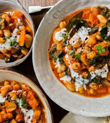 Photo shows three dishes of stew made with beans, kale, and lemon