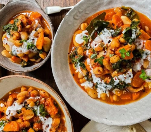 Photo shows three dishes of stew made with beans, kale, and lemon