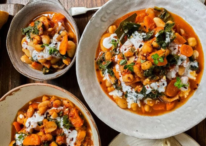 Photo shows three dishes of stew made with beans, kale, and lemon