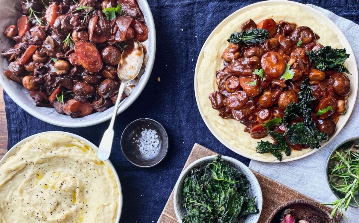 Photo shows two bowls of mushroom bourguignon served with white bean mash and kale crisps